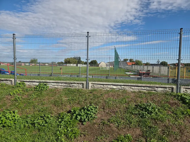 Ocynkowane ogrodzenie panelowe na podmurówce o fakturze łupka przy boisku w Domaszkowicach