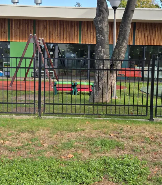 Czarne ogrodzenie ozdobne z pionowych prętów przy żłobku miejskim w Nysie